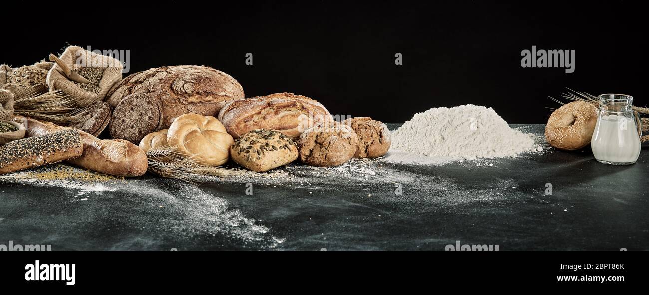 Display Panorama gourmet di pane con la pasta di pane, latte e farina ingredienti oltre un infarinato e tavolo da cucina con spazio di copia Foto Stock