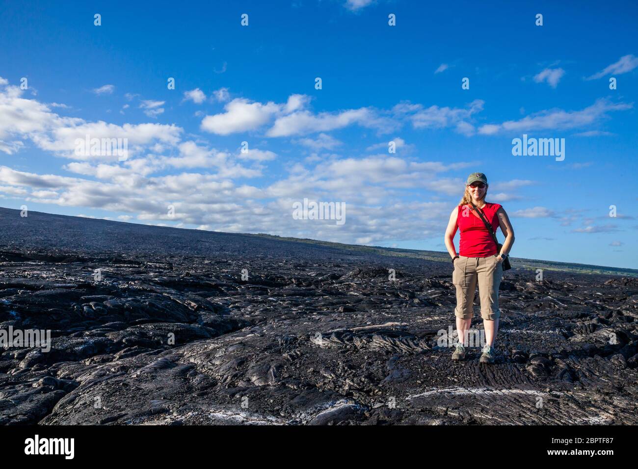 Una donna che posa per una foto sui grandi campi di lava della zona di Rift orientale, 2017 mentre si cammina verso il punto di ingresso dell'oceano di lava lungo la catena di Foto Stock