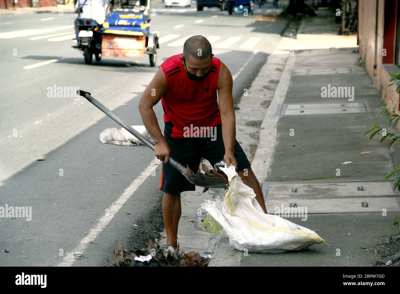 Città di Antipolo, Filippine - 16 maggio 2020: L'uomo spazza sporcizia e altri detriti dopo una notte di forte pioggia e vento causati dal tifone Ambo o Vongfo Foto Stock