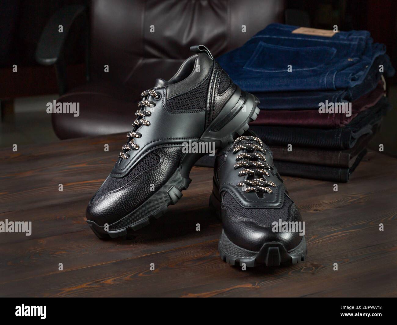 Un paio di sneaker da uomo in pelle su un tavolo in un negozio di abbigliamento. Primo piano, messa a fuoco selettiva. Pile di jeans Foto Stock