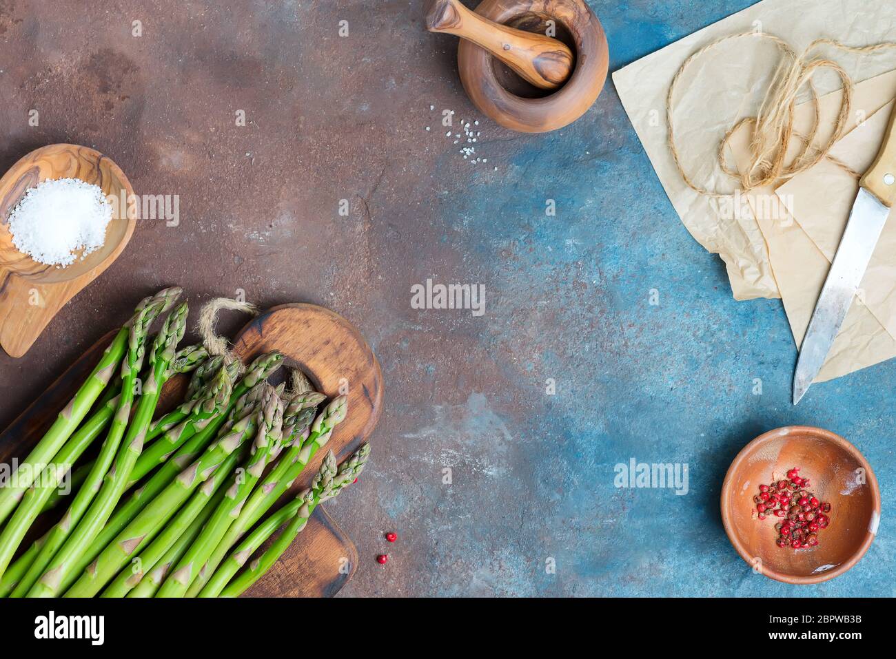 Le lance grezze di asparagi verdi organici su una tavola di legno come alimento sano di dieta su un fondo scuro della pietra. Foto Stock