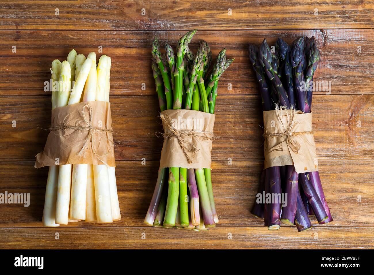 Spighe di asparagi biologici di colore naturale e fresco su sfondo ligneo. Vista dall'alto. Foto Stock