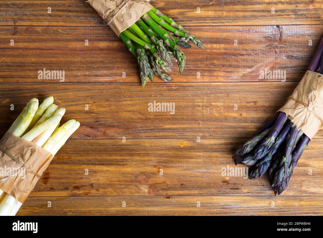 Spighe di asparagi biologici di colore naturale e fresco su sfondo ligneo. Vista dall'alto. Foto Stock