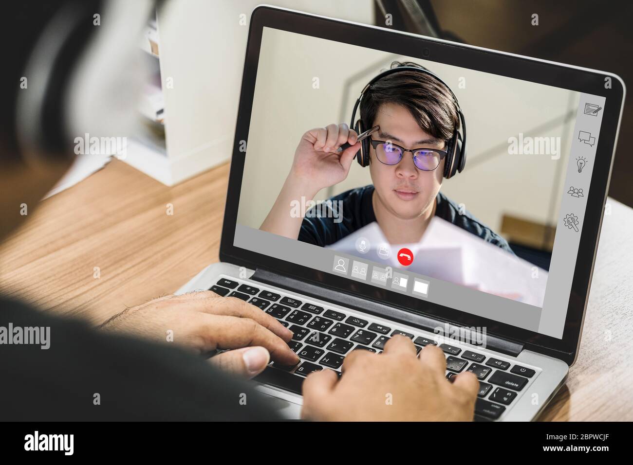 Uomo d'affari asiatico che indossa cuffie e utilizza un computer portatile per videoconferenza con un collega a una riunione online quando Coronavirus focolaio, Covid-19 pandem Foto Stock Uomo d'affari asiatico che indossa cuffie e utilizza un computer portatile per videoconferenza con un collega a una riunione online quando Coronavirus focolaio, Covid-19 pandem Foto Stock