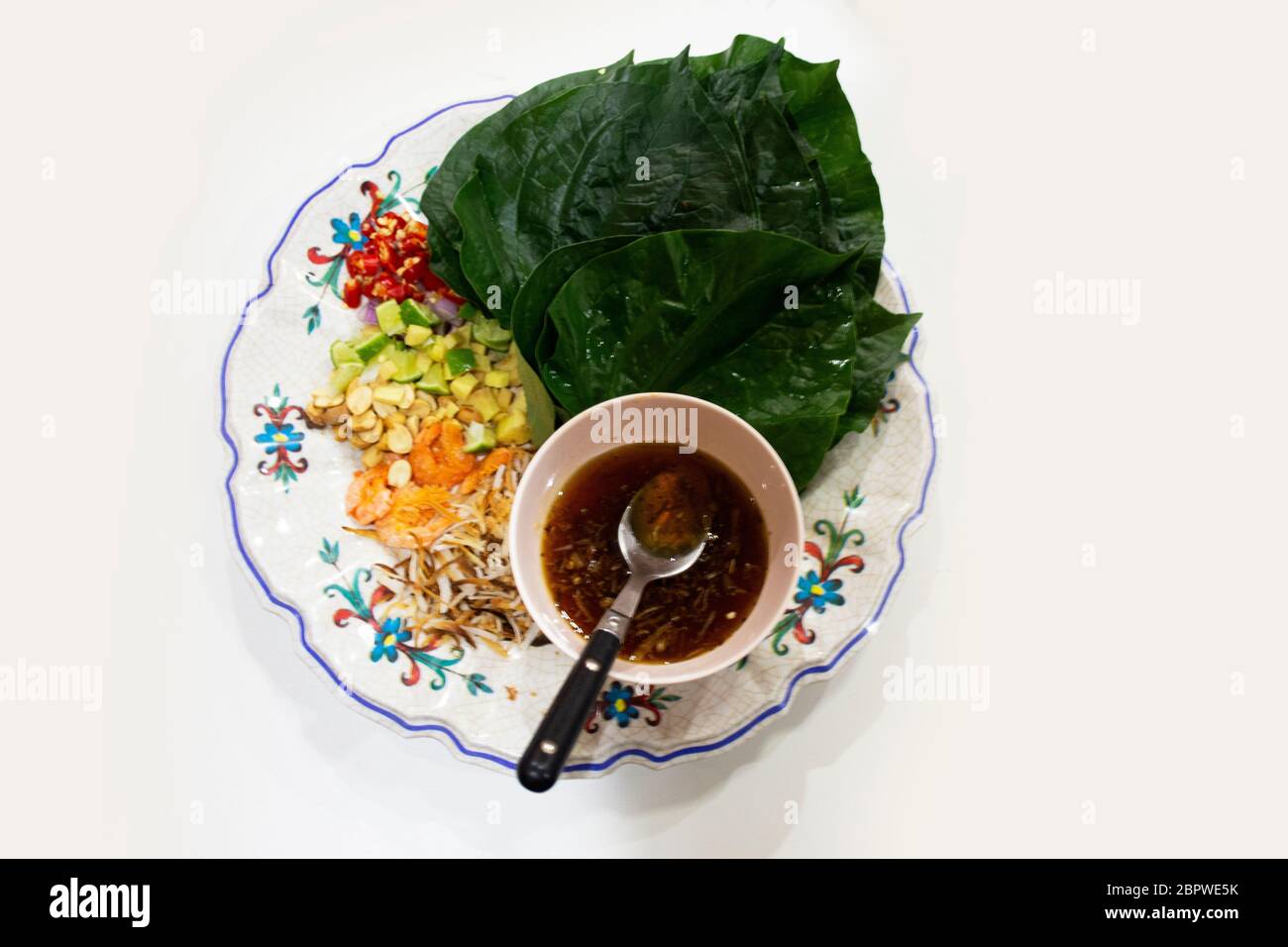 Spuntini Thai Miang Kham o un antipasto reale di involtino di foglie salate in piatto di ceramica servire con salsa dolce al caramello nel ristorante locale della Thailandia Foto Stock