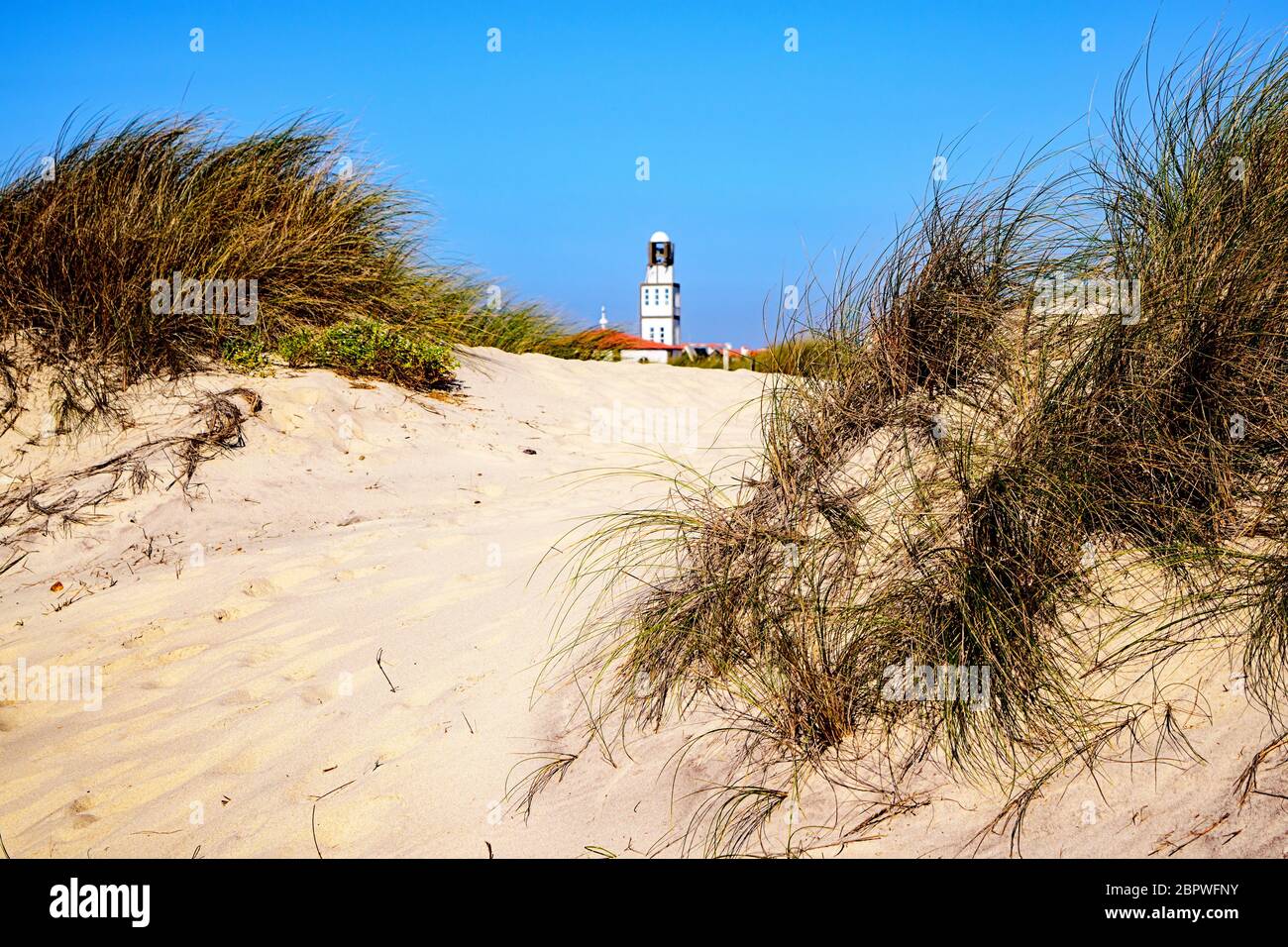 Il campanile della chiesa di nostra Signora della Salute sorge sopra le dune di sabbia a Praia da Costa Nova, Portogallo Foto Stock