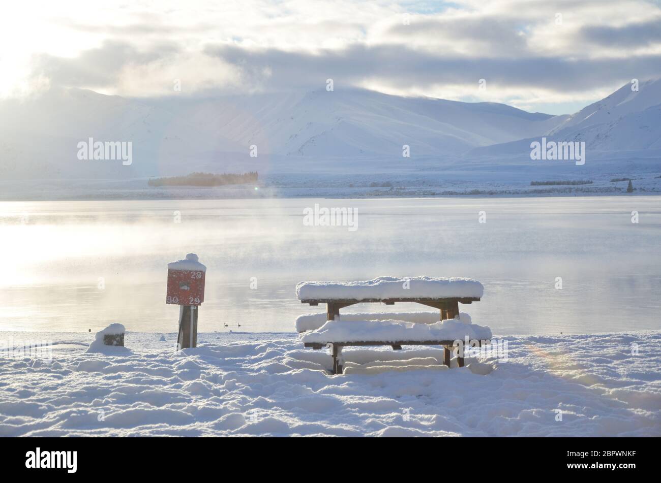 Alba sul lago Tekapo con una porta di ricarica e panca durante l'inverno. Foto Stock