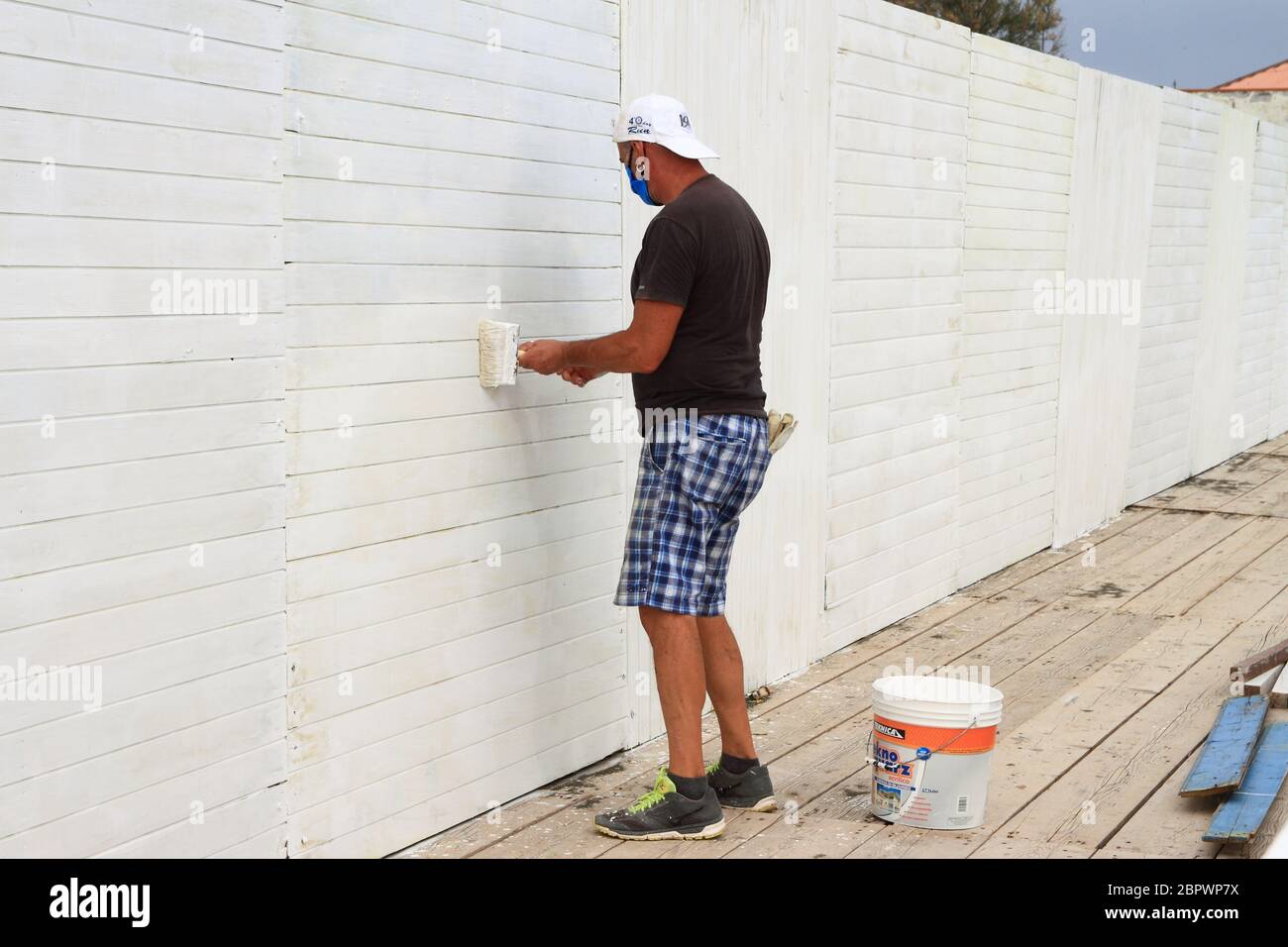 Un operaio dipinge con il colore bianco un muro di una cabina del lido prima della riapertura della spiaggia ai clienti per la nuova stagione estiva. Foto Stock