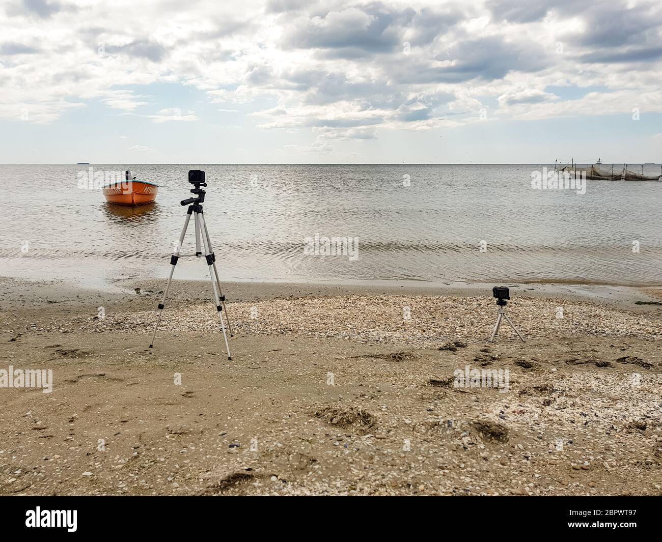 Due film d'azione cattureranno il tempo trascorso dal mare con una vecchia barca di salvataggio arancione in riva al mare, ancorata con l'iscrizione di salvataggio Foto Stock