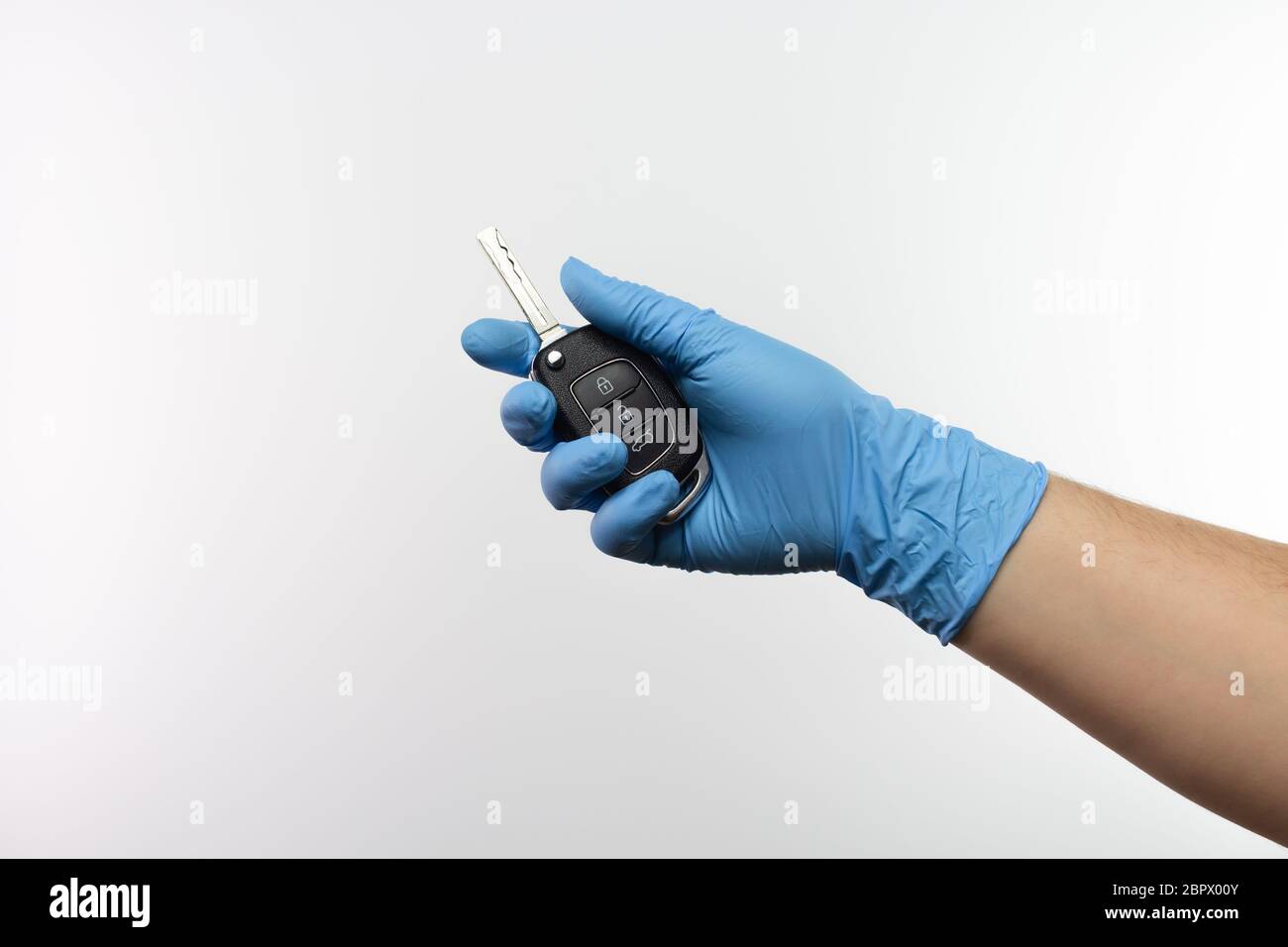 Mano con guanti protettivi che tengono una chiave per auto Foto Stock