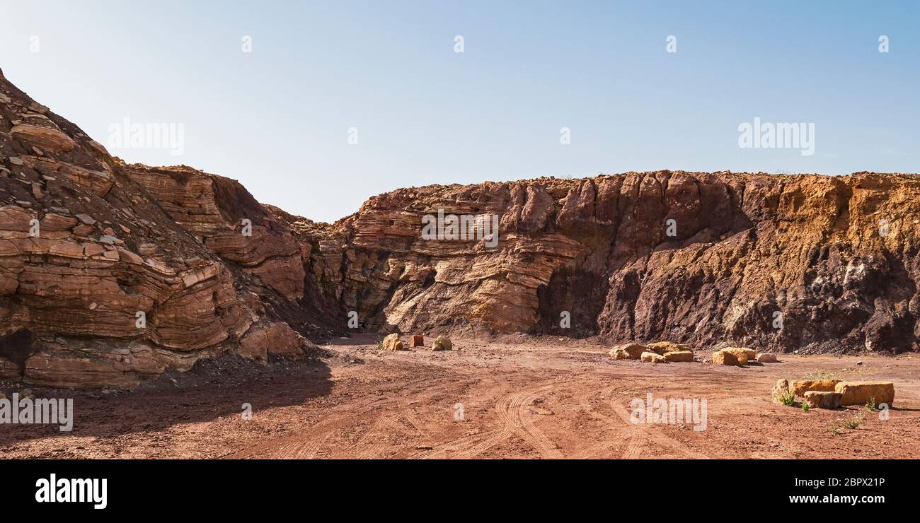 Strati di calcare dominano la sinistra e la metà di questa cava abbandonata nel cratere Ramon in Israele, mentre vari depositi di argilla sono sulla destra Foto Stock