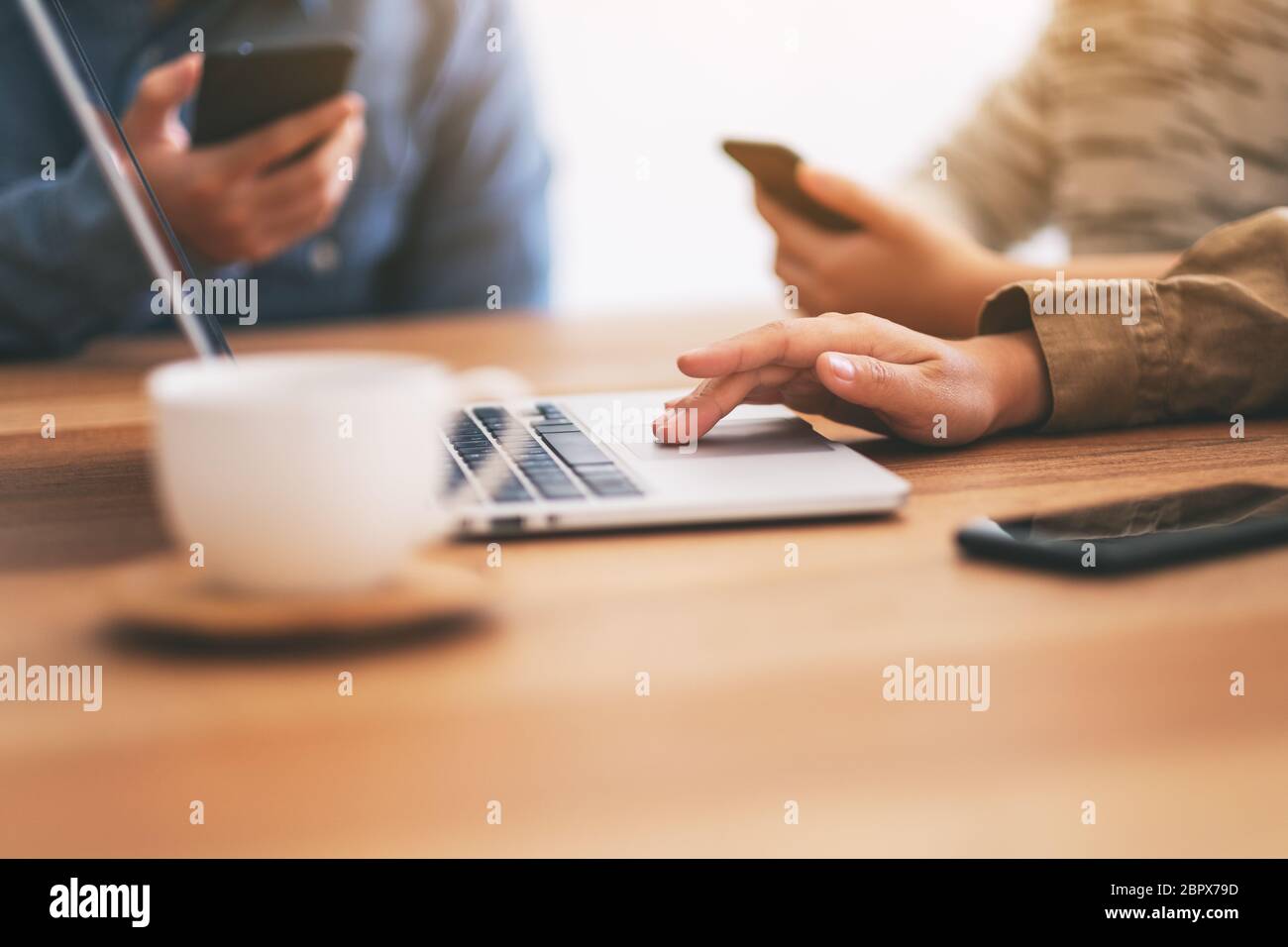 Primo piano immagine di persone che utilizzano il telefono cellulare e il computer portatile sul tavolo di legno Foto Stock