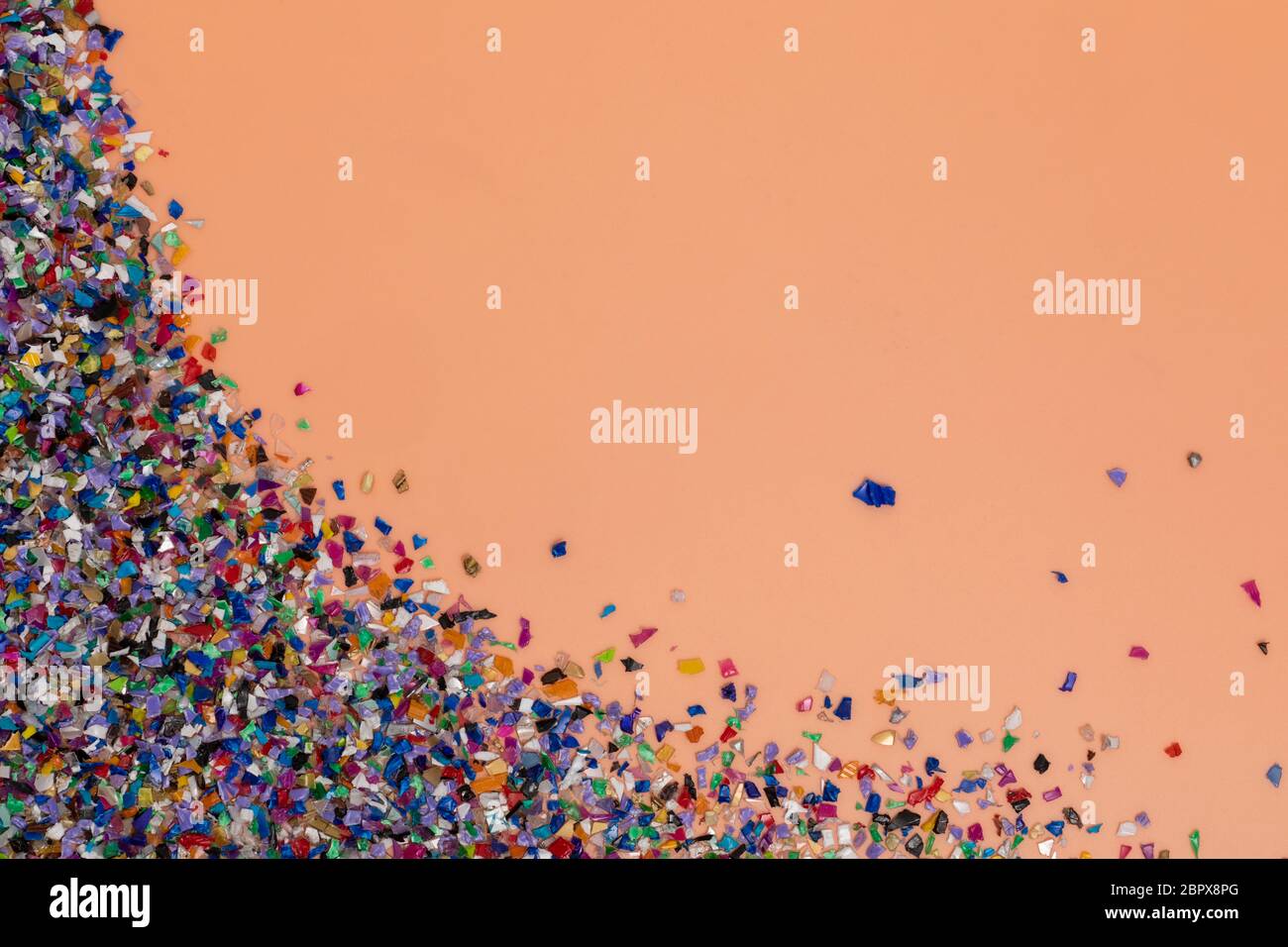 Pellet di plastica riciclata raccolti dall'acqua di mare, flatlay su un morbido sfondo arancione. Pezzi colorati. Ripensare l'ambiente riducendo o Foto Stock
