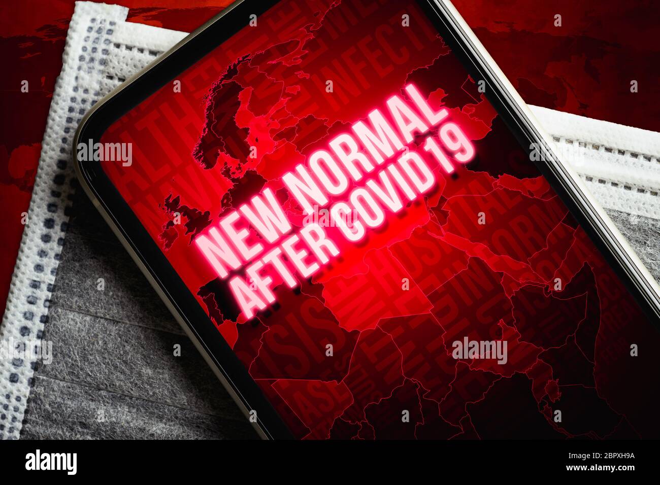 Il nuovo concetto di sfondo normale dopo Covid-19. Uno smartphone con nuovo normale dopo covid19 messaggio con mappa del mondo sulla maschera medica viso su grunge Foto Stock
