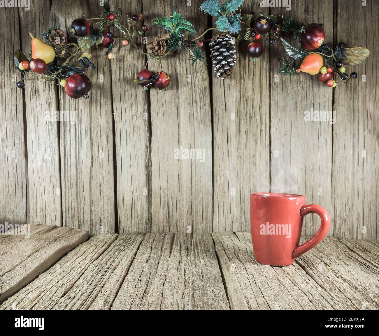 Una tazza rossa di caffè con ornamento di Natale sul vecchio pannello di legno di sfondo. Foto Stock