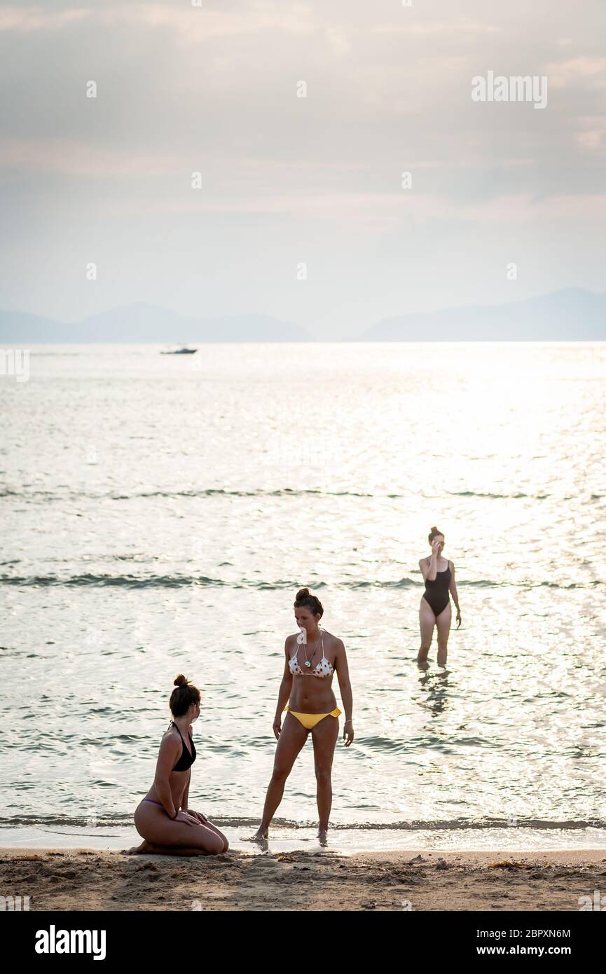 Le coppie si sfilano in acqua per godersi e fotografare il tramonto a Las Cabanas Beach, El Nido, Palawan, Filippine. Foto Stock