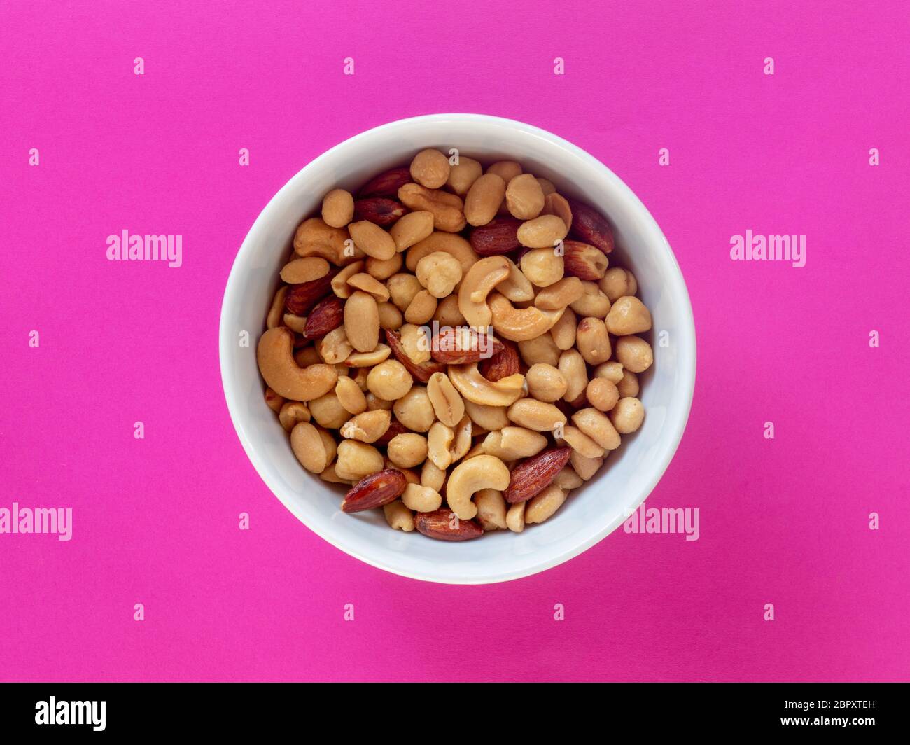 Miscela di nocciole arrosto isolata su sfondo rosa Foto Stock