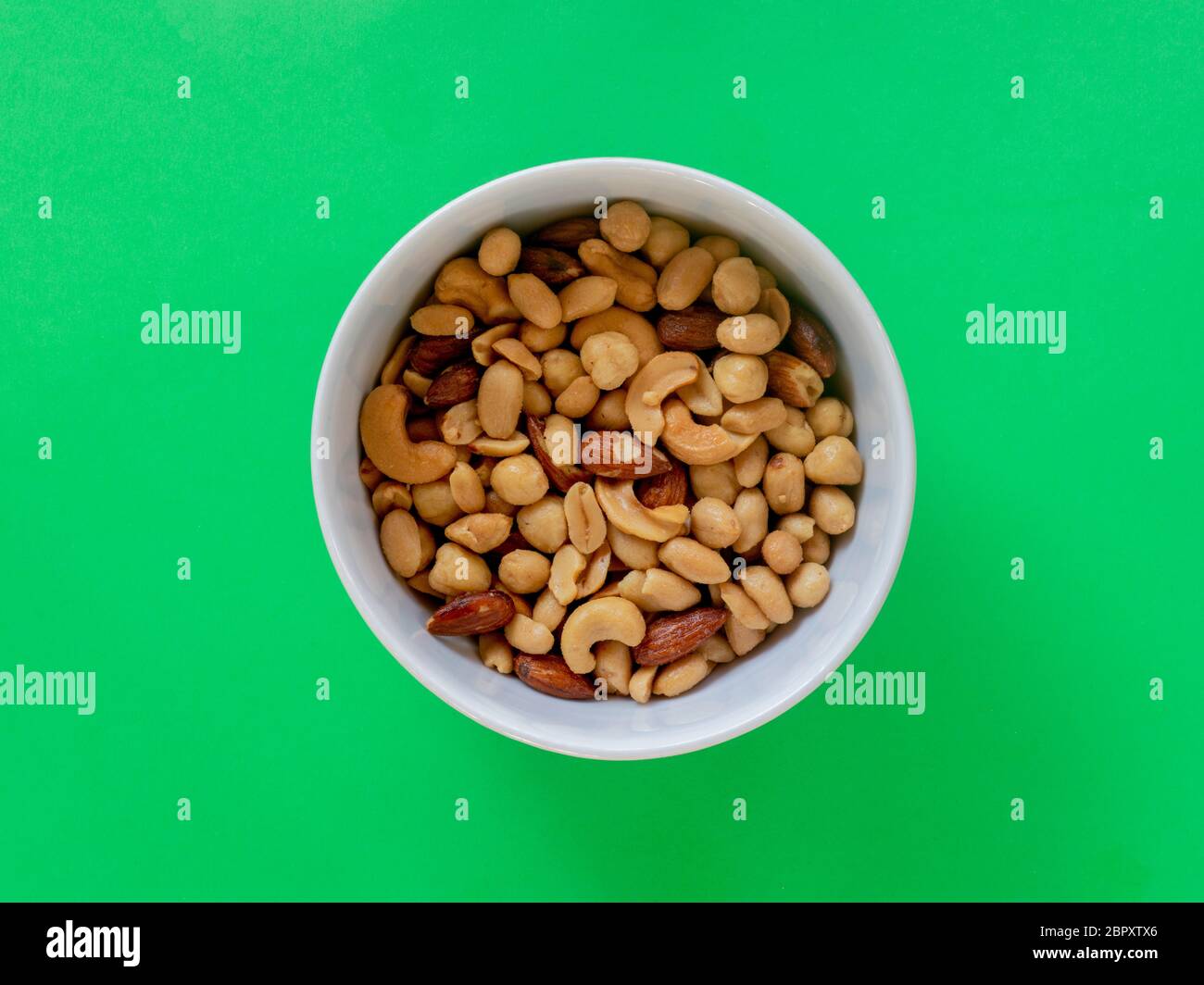 Miscela di nocciole arrosto isolata su sfondo verde Foto Stock