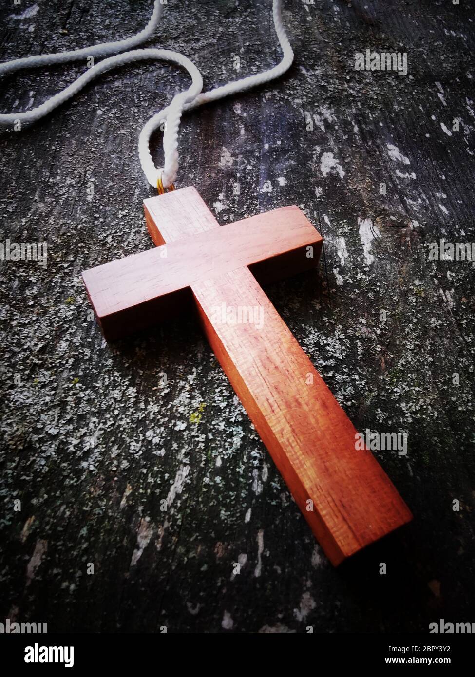 Primo piano verticale di una collana a croce con perline rosse su una scatola sul tavolo sotto le luci Foto Stock