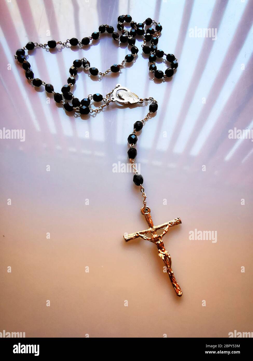 Primo piano verticale di una collana a croce con perline nere sul tavolo  sotto le luci Foto stock - Alamy