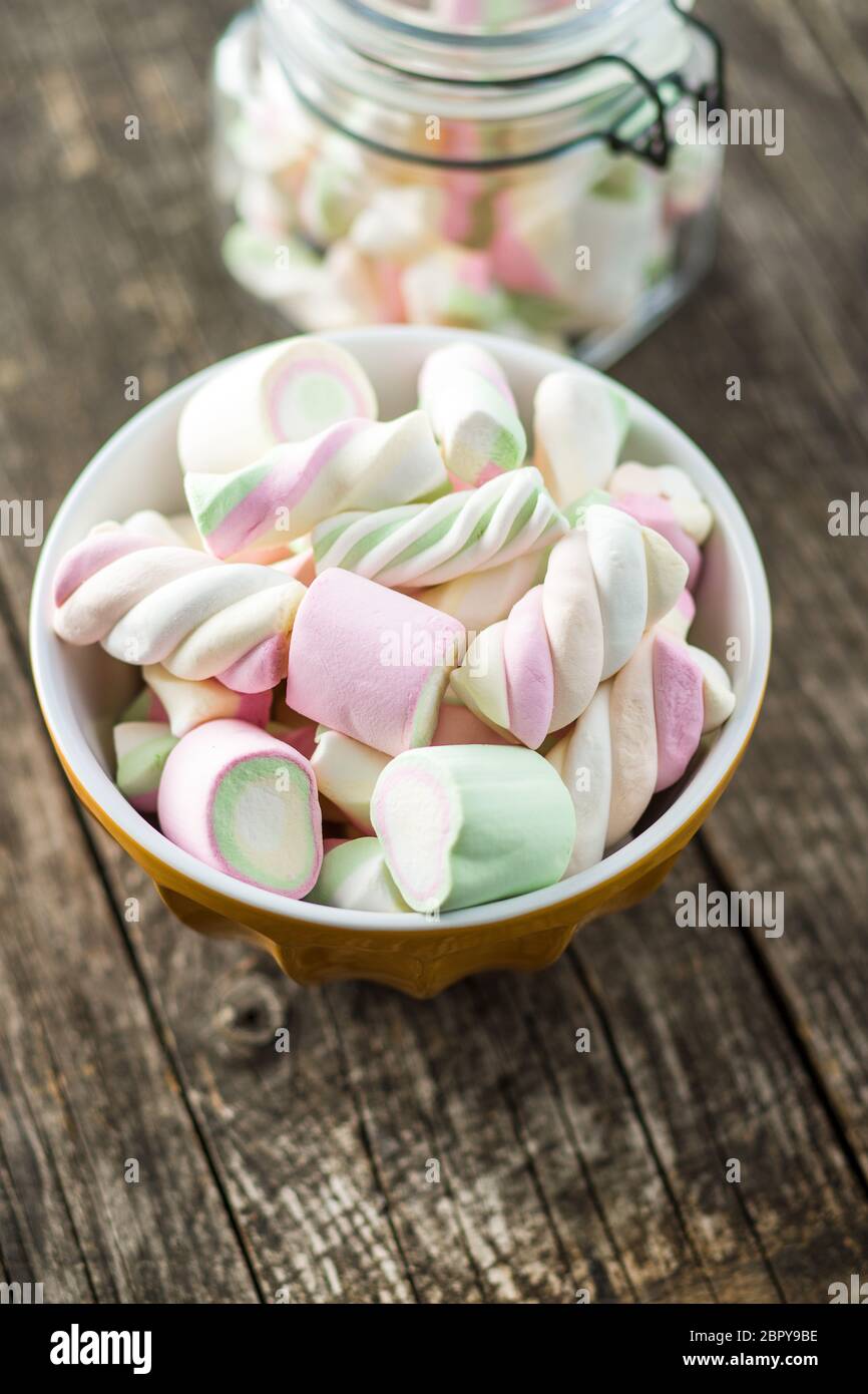 Dolci marshmallows colorati nella ciotola sul tavolo di legno. Foto Stock