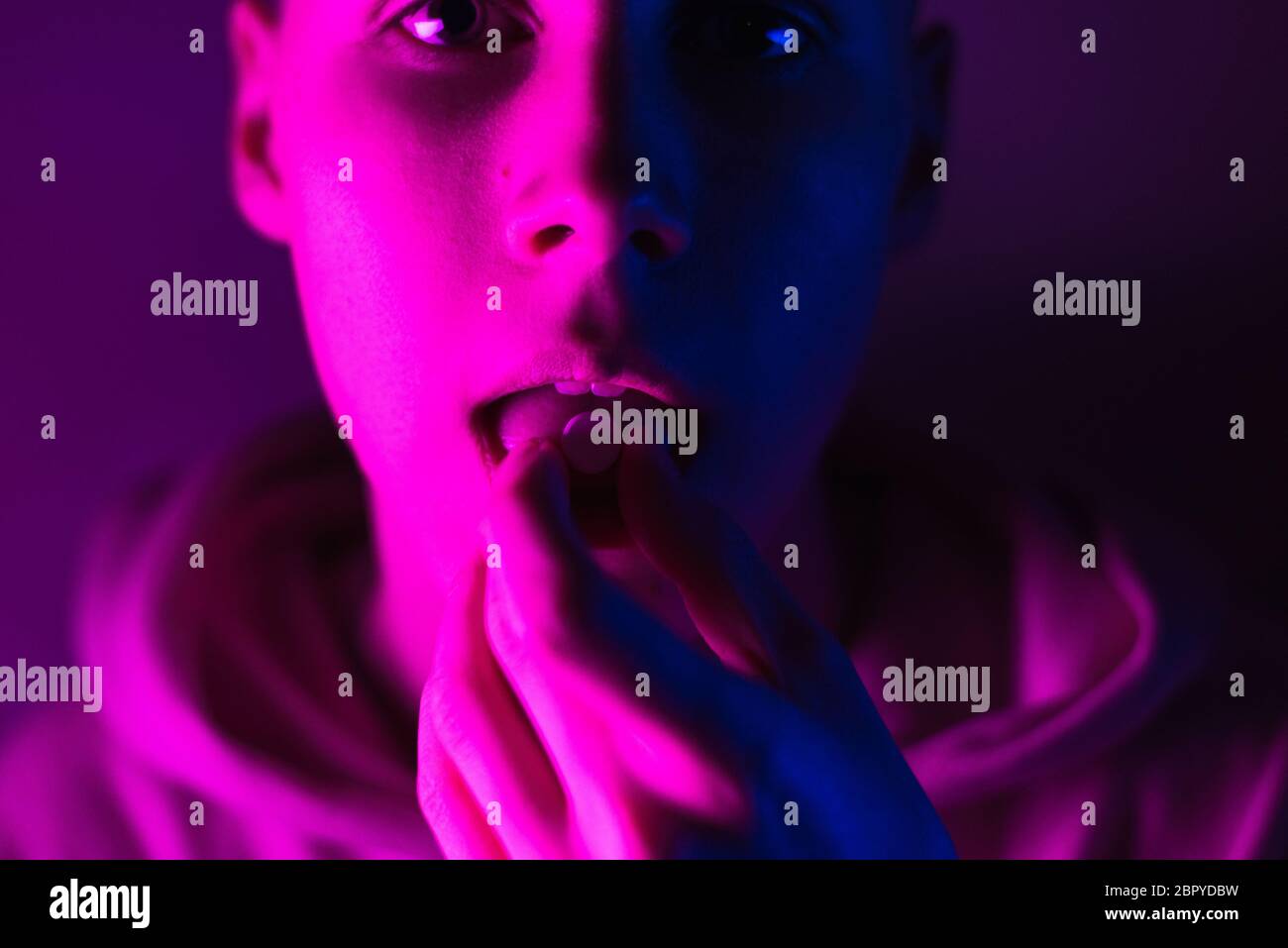 Giovane adolescente in una felpa con cappuccio rosa prende una droga in pillole. Tipo di timone con ruota lsd. Foto Stock