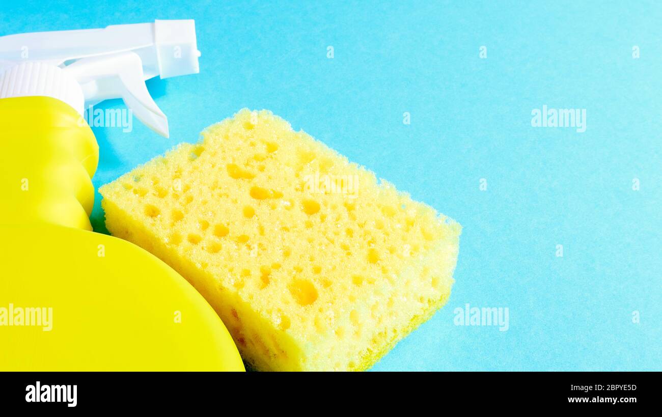 Set di prodotti per la pulizia su sfondo blu. Panno e spugna gialla, spray detergente, detergente. Concetto di pulizia della casa Foto Stock