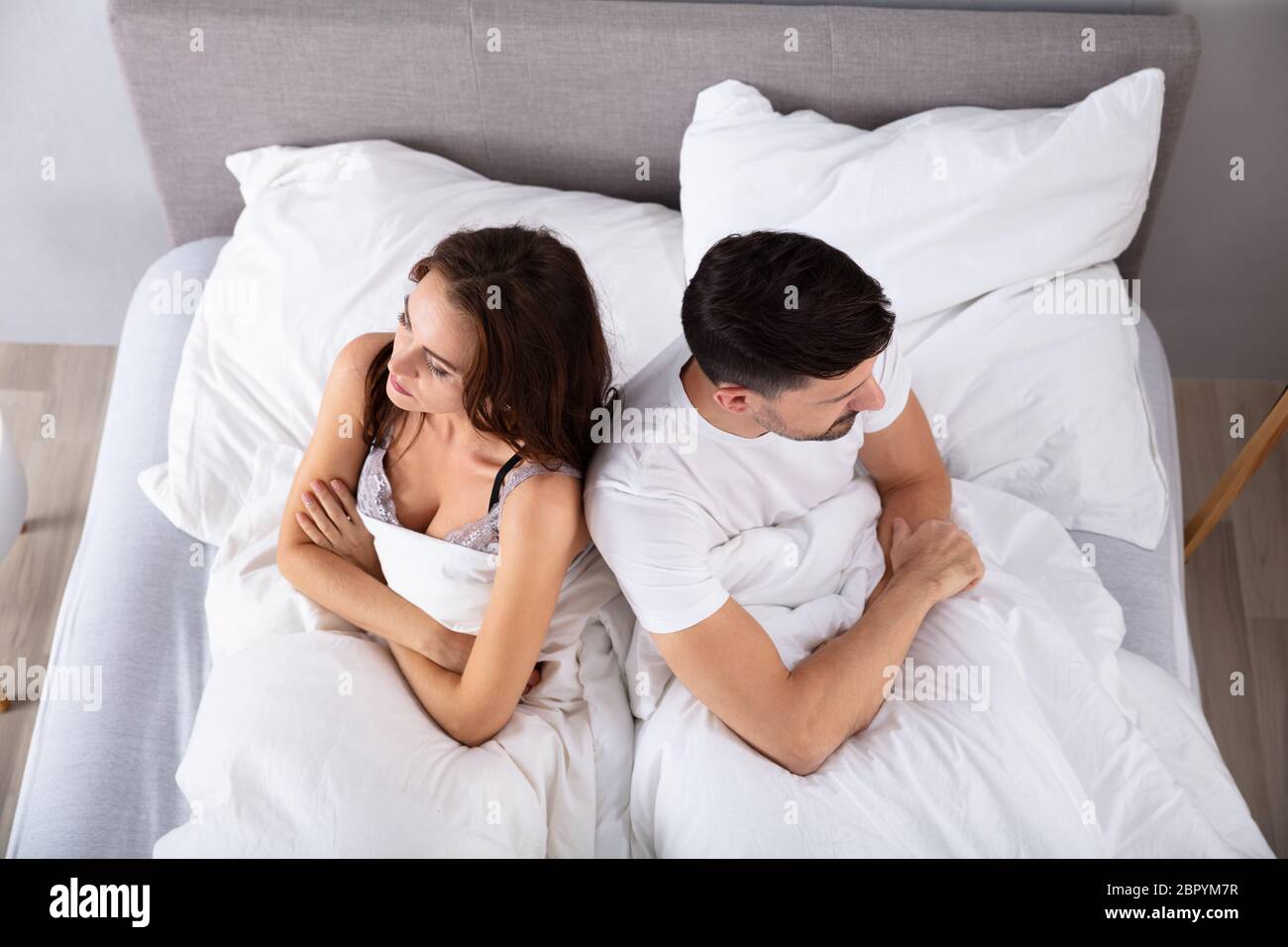 Vista superiore del disperato della coppia di coniugi di schiena sul letto Foto Stock