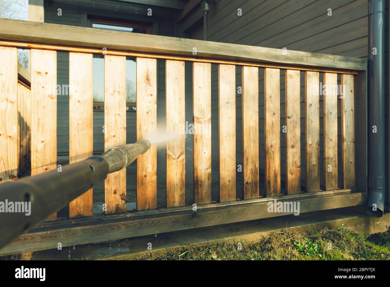 Pulizia uomo terrazza con una rondella di potenza - Elevata pressione dell'acqua detergente su terrazza in legno ringhiera Foto Stock