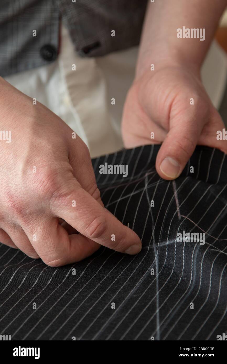 Uomo sarto che lavora nel suo negozio di sartoria, cucire a mano tessuto di lana nera scura per il vestito. Processo di tuta realizzata a mano su misura con feltro e ago Foto Stock