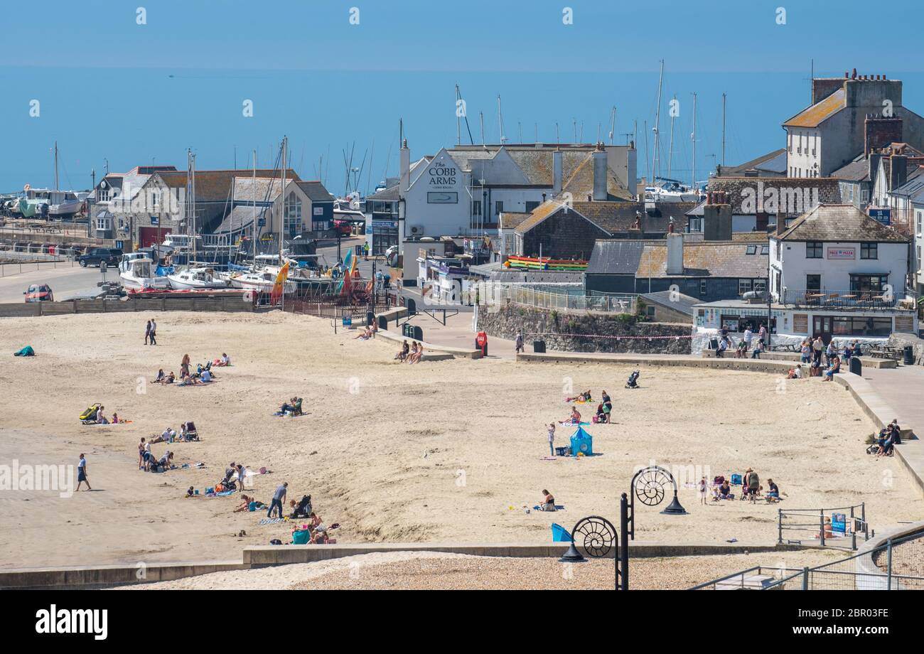 Lyme Regis, Dorset, Regno Unito. 20 Maggio 2020. Regno Unito Meteo. I beachgoers si immergersi in un sole caldo bruciante alla stazione balneare di Lyme Regis il giorno più caldo dell'anno finora. La gente sta cominciando a liberarsi dal blocco pandemico del coronavirus e godere la mini-ondata di calore in anticipo del fine settimana della festa della banca. Credit: Celia McMahon/Alamy Live News Foto Stock