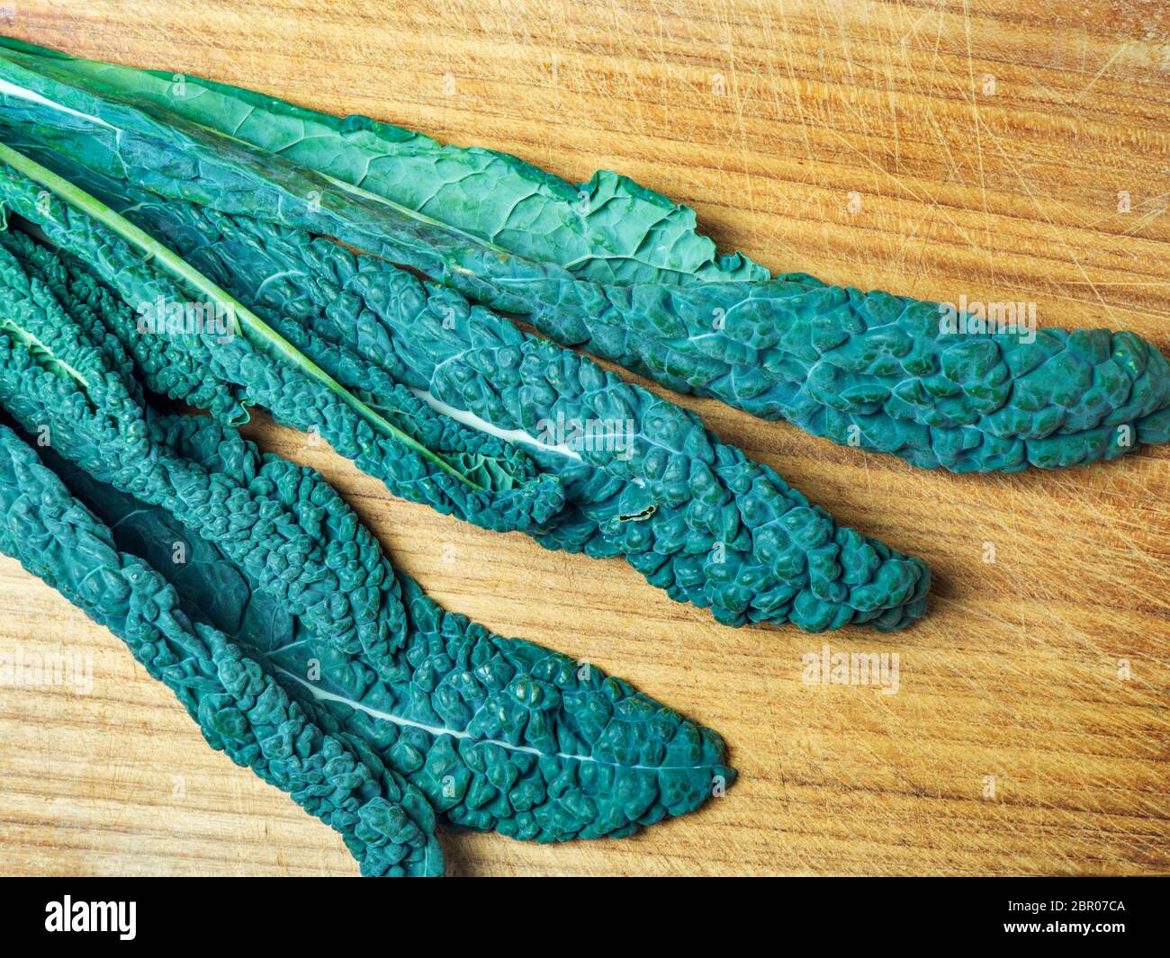 Il cavolo nero o il cavolo nero si trova su una taglierine di legno Foto Stock