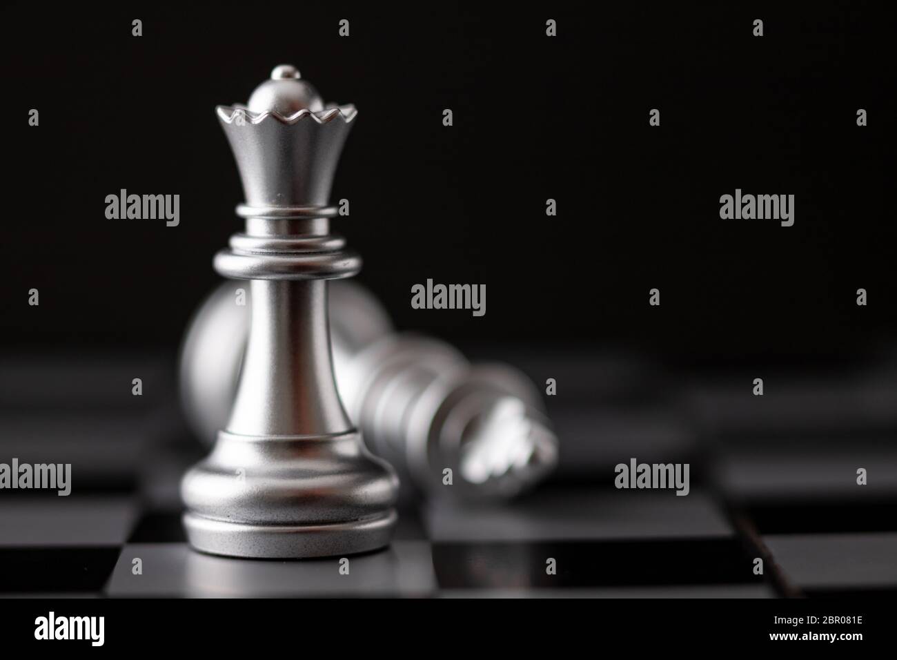 La regina d'argento in piedi e il re che cade in gioco sulla scacchiera Foto Stock