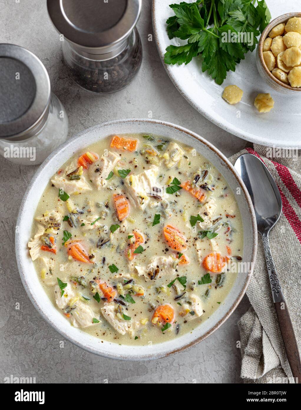 Vista dall'alto di una ciotola di zuppa di pollo e riso cremosa con carote e prezzemolo Foto Stock