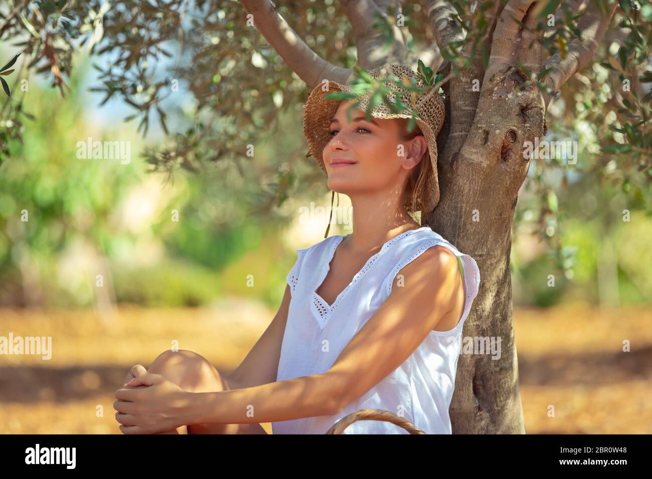 Donna pacifica con piacere in appoggio nelle olive garden, bella ragazza agricoltore godendo la freschezza di una molla natura, vita felice in una campagna Foto Stock
