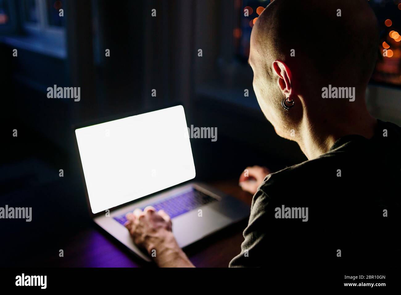 Uomo che lavora con un notebook da casa di notte. Spia blu dello schermo Foto Stock