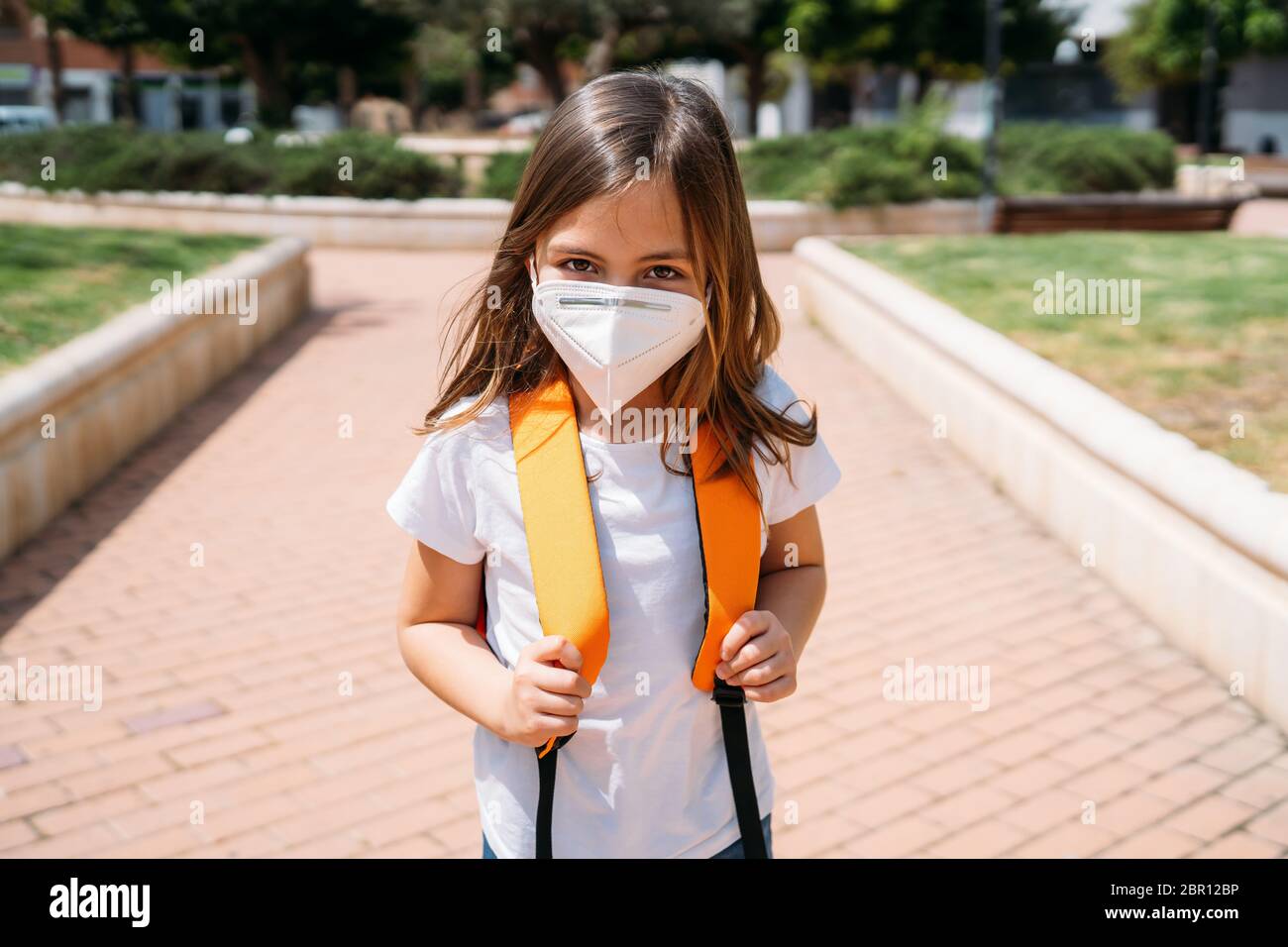 Bambina con maschera in un parco durante la pandemia del coronavirus Foto Stock