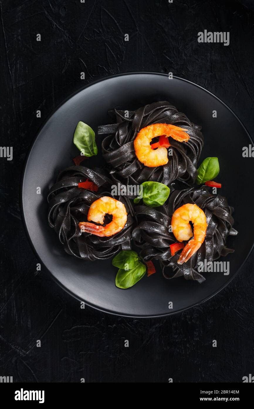 Calamari inchiostrato tagliatelle con gamberi su sfondo nero. Foto Stock