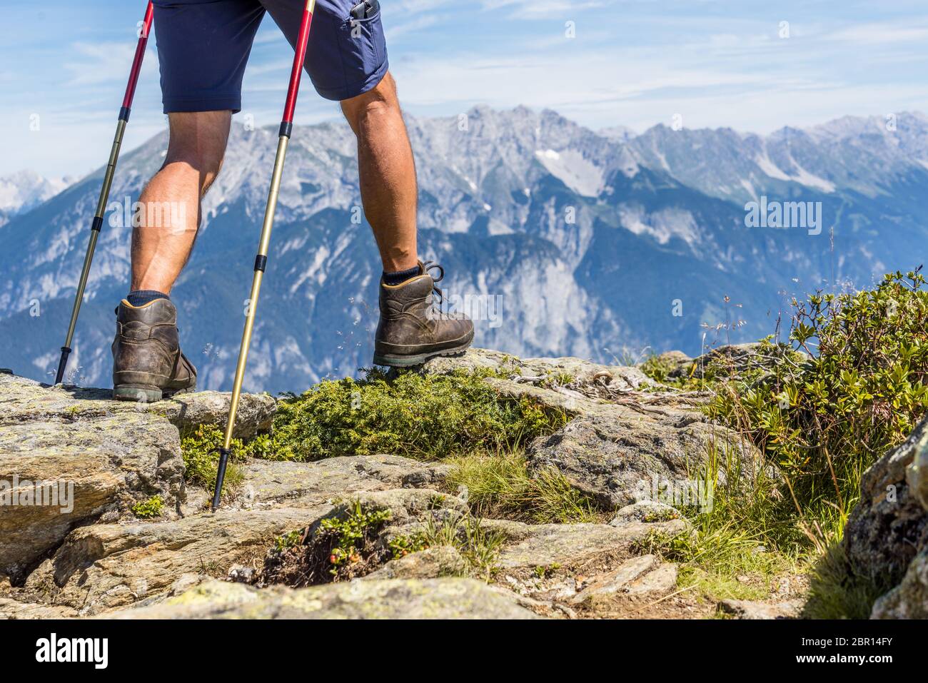 Primo piano di gambe maschili muscolose e venose con bastoncini da trekking per il nordic walking sullo sfondo della catena montuosa alpina della Valle Ziller, Foto Stock