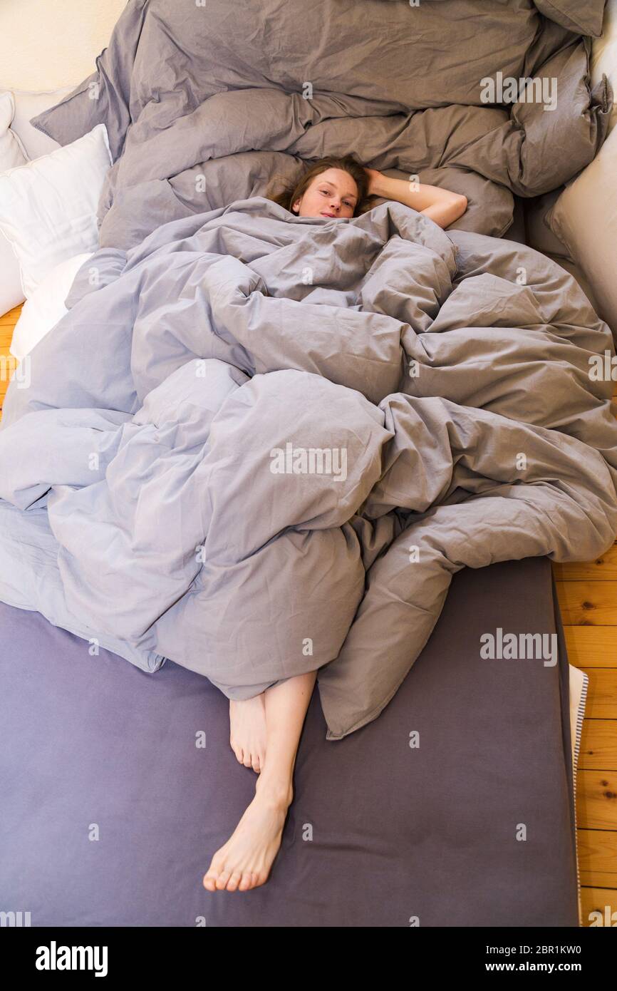 la ragazza nel letto si trova sotto le coperture con le gambe bastone fuori  Foto stock - Alamy