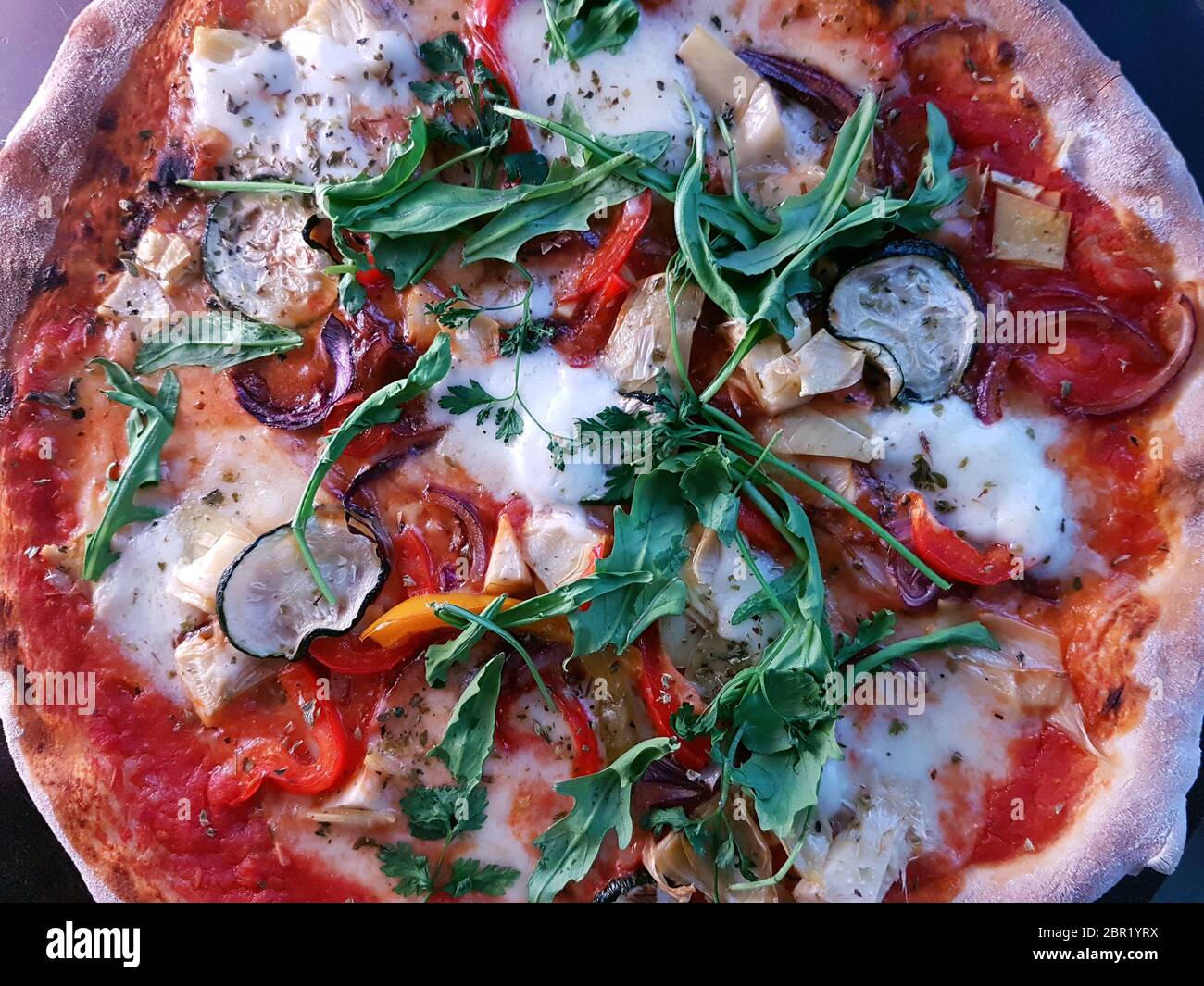 Pizza cotta in stile mediterraneo cotta a legna con un razzo fresco Foto Stock