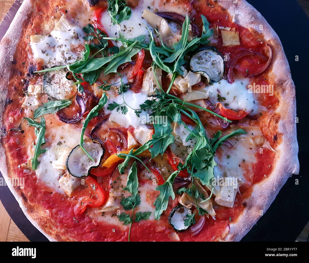 Pizza cotta in stile mediterraneo cotta a legna con un razzo fresco Foto Stock