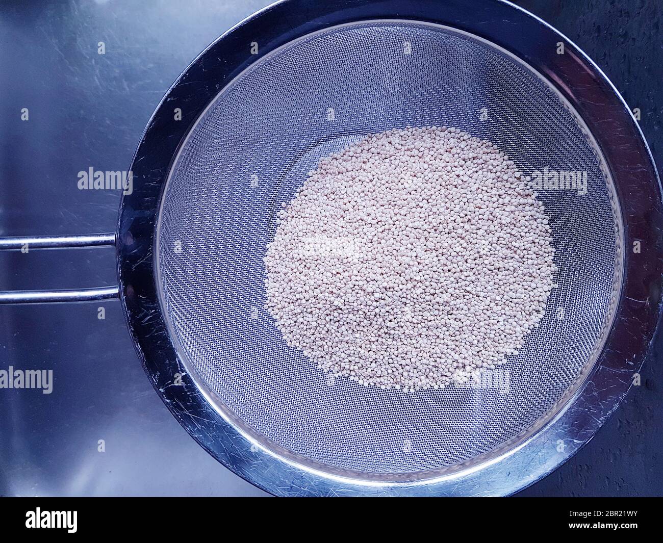 Quinoa non cotti in un setaccio da cucina per il lavaggio Foto Stock