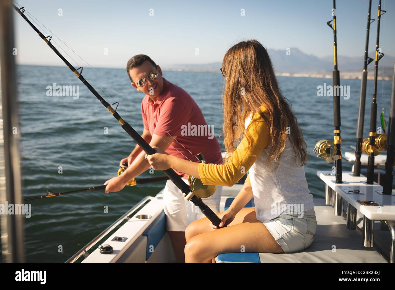 Un uomo caucasico e la sua figlia adolescente che tiene canne da pesca e parla Foto Stock