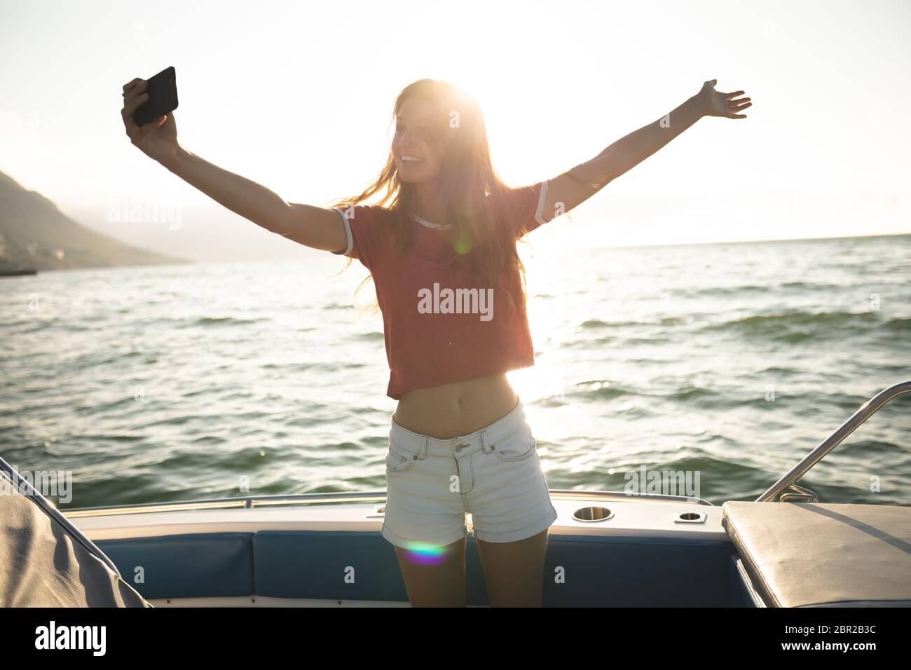 Una ragazza caucasica adolescente in piedi su una barca e prendendo un selfie Foto Stock