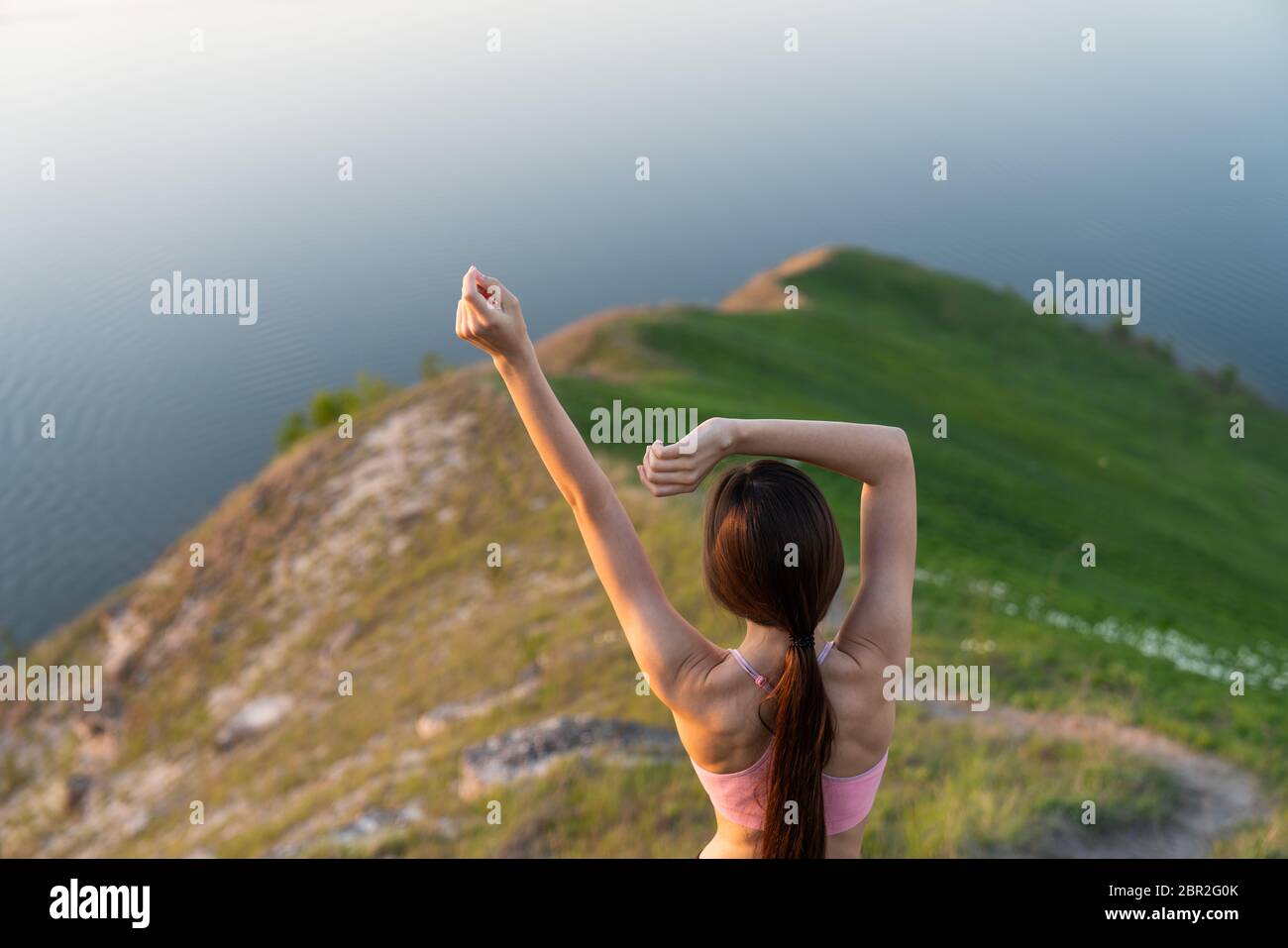 Donna escursionista in piedi con le mani fino a raggiungere la cima. Donna di successo escursionista aprire le braccia sulla cima di montagna alba Foto Stock