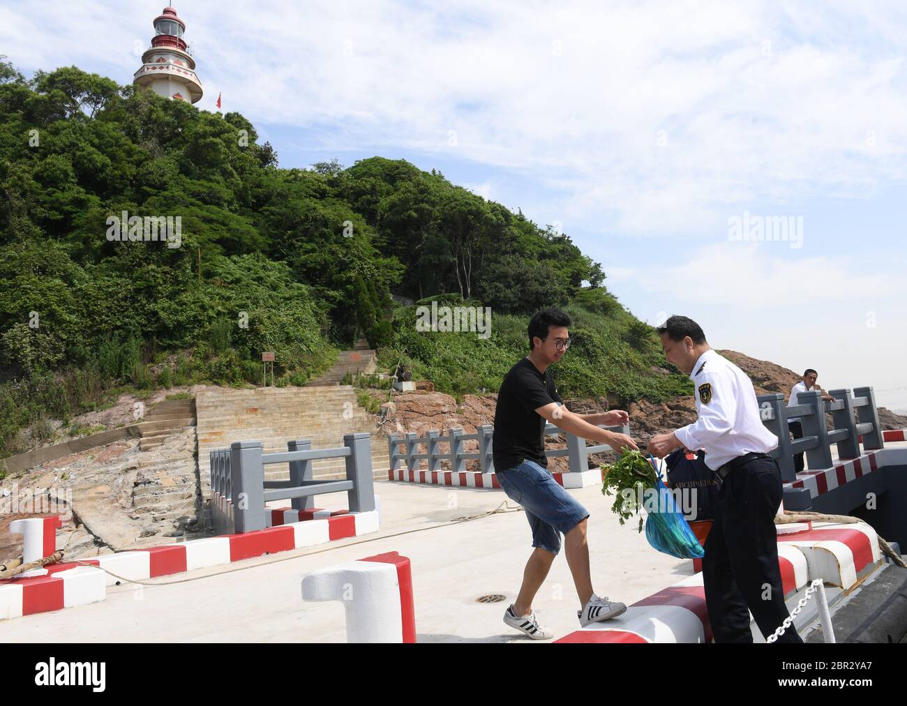 (200520) -- NINGBO, 20 maggio 2020 (Xinhua) -- Ye Chaoqun (L), un guardiano del faro di quinta generazione, riceve verdure fresche dal padre, Ye Jinghu, che porta le necessità quotidiane, sull'isola di Qiliyu a Ningbo, provincia di Zhejiang, nella Cina orientale il 20 maggio 2020. Cinque generazioni di una famiglia di Ningbo, provincia di Zhejiang, nella Cina orientale, hanno servito come guardiani del faro, adottando un motto di famiglia che è 'tenere la luce accesa quando si è vivi' risolutamente. Nel 1883, Ye Lairong, primo guardiano della famiglia, iniziò a lavorare sull'isola di Baijie. Dopo di che, i suoi discendenti ereditati e devoti t Foto Stock