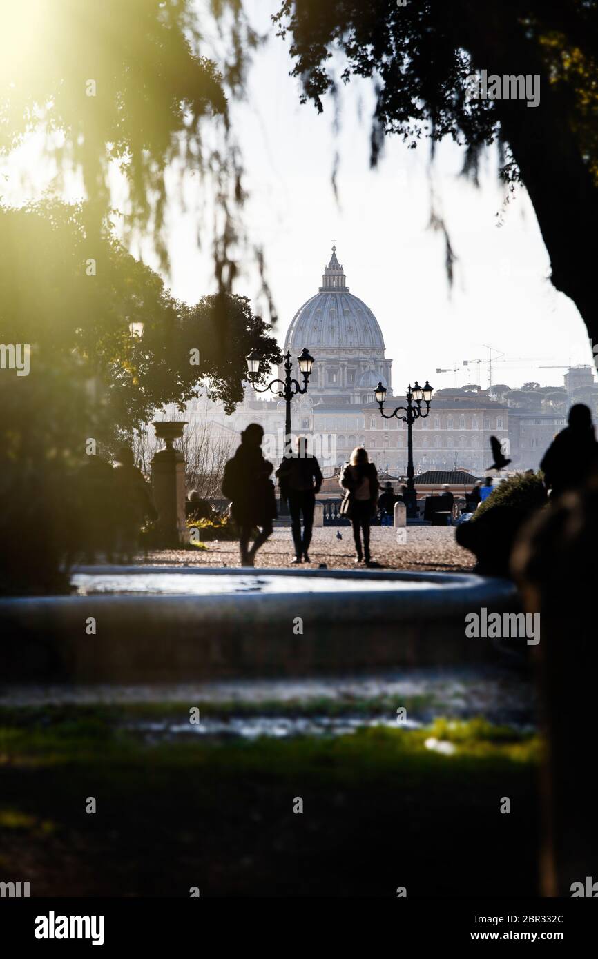 Basilica di San Pietro vista dal parco di Villa Borghese a Roma. Una fontana e pochi turisti a piedi. Luce luminosa dall'alto. Giorno all'aperto. Foto Stock