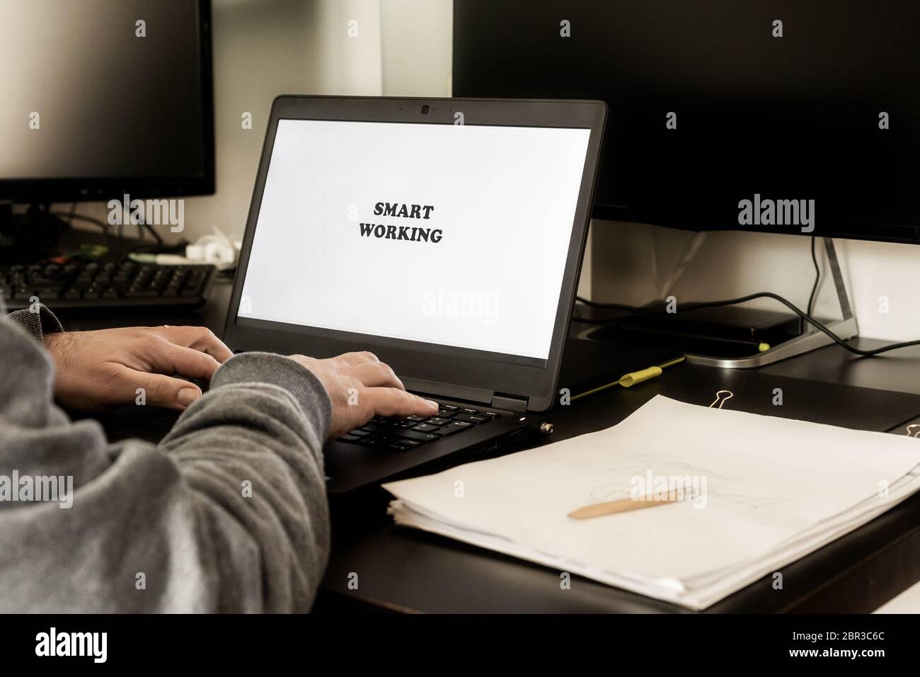 Vista posteriore dell'uomo che utilizza un computer portatile per lavorare in modo intelligente da casa. Lavoro intelligente scritto sul display. Concetto di lavoro agile. Foto Stock
