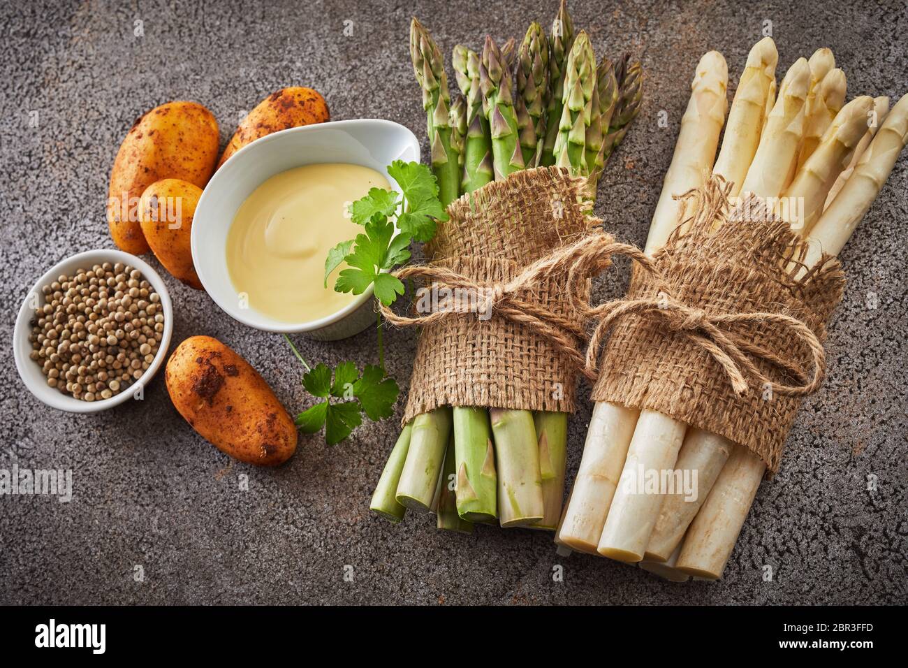 Gli ingredienti freschi per starter di asparagi con patate novelle di pepe, la maionese, il coriandolo e due fasci di bianco e asparagi verdi spears Foto Stock